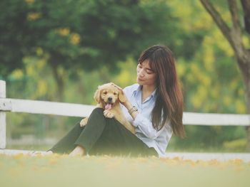 Woman with puppy sitting on field at public park