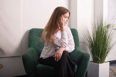 A young girl in a white shirt is sitting in a chair in the psychologist's office