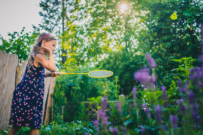 Midsection of woman standing against plants in yard