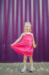 Full length of young woman standing against wall