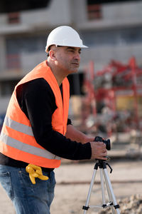 Side view of man holding camera at construction site