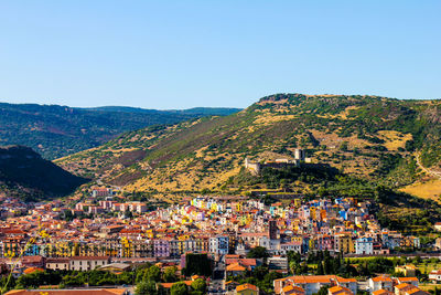 Aerial view of townscape and mountains against clear blue sky