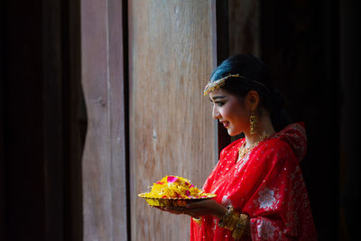 Side view of woman looking away against door