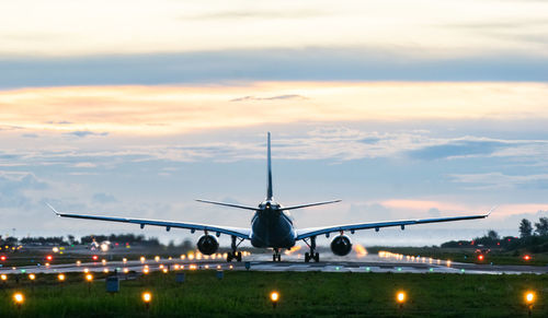 Airplane flying in sky at sunset