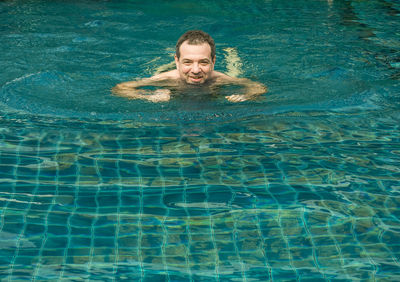 Portrait of smiling man swimming in pool