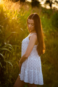 Young beautiful woman in white dress in corn field.