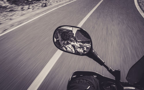 Reflection of man photographing in motorcycle mirror