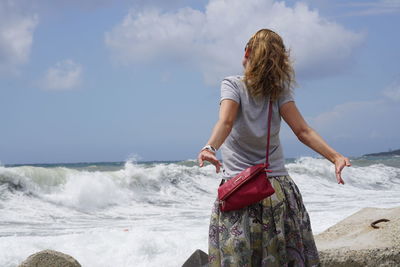 Woman standing at beach against sky