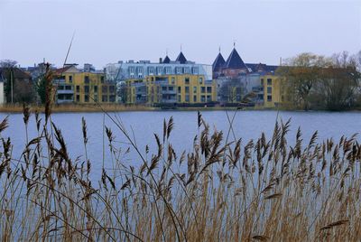 Buildings by river against clear sky