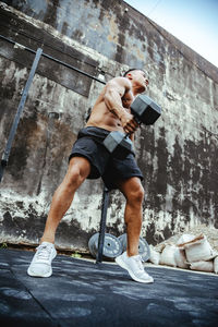 Full length of shirtless man climbing outdoors