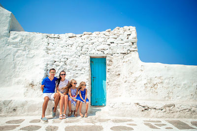 Rear view of people walking on beach against clear blue sky