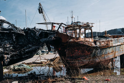 Abandoned fishing boat in water against sky