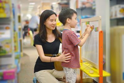 Mother assisting son in sticking number on whiteboard