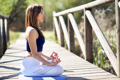 Profile view of woman meditating on footbridge