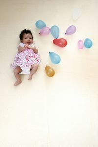 Portrait of cute baby girl with balloons lying on bed