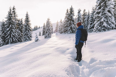 Rear view of man walking on snow covered landscape