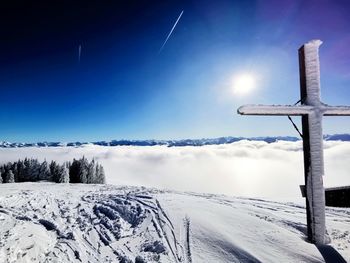 Snow covered cross against blue sky