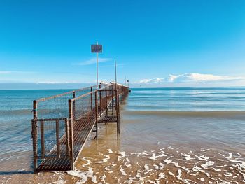 Wooden posts on beach against sky
