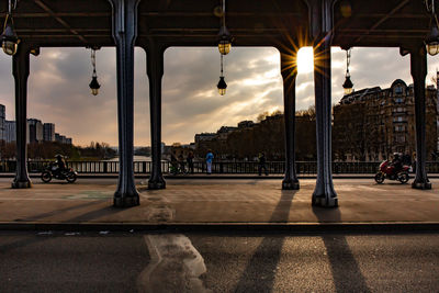 People on street in city against sky at sunset