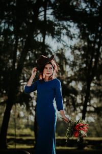 Young woman wearing hat standing against plants