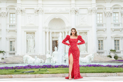 Portrait of young woman standing against building