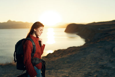 Young woman on beach against sky during sunset