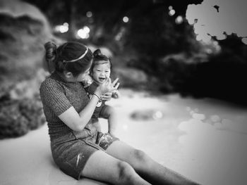 Rear view of happy girl holding water while sitting against sky