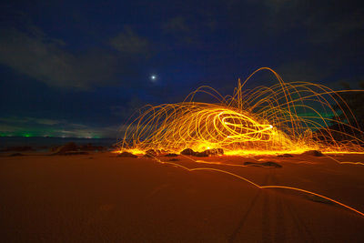 Light trails on road against sky at night