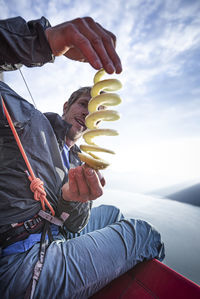 Man sitting on portaledge at sunset looking at apple peeler product