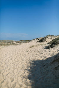 Surface level of sandy beach against clear blue sky