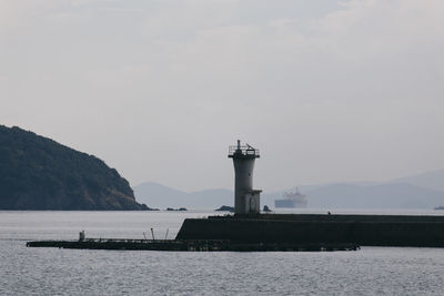 Lighthouse by sea against sky