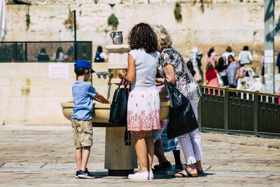 Rear view of people walking in front of built structure