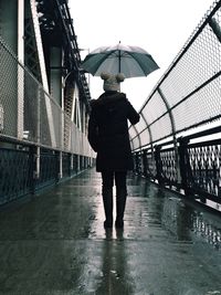 Young woman with umbrella standing on bridge