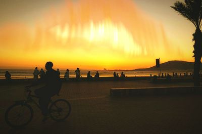 Silhouette people on beach against sky during sunset