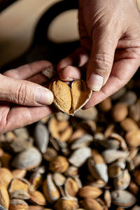 Close up of male hands holding a heart shaped raw almond.