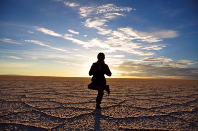Silhouette of person practicing yoga on salt flat