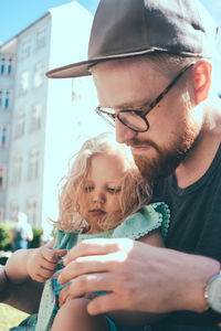 Father and daughter looking at something while sitting in city