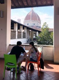 Rear view of people sitting on seat outside building