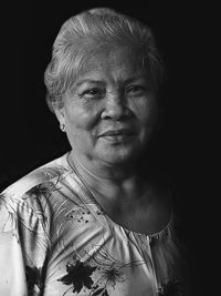 Portrait of senior woman against black background