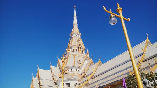 Low angle view of thai temple against clear blue sky