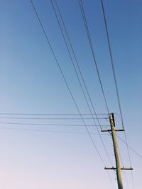 Low angle view of electricity pylon against clear blue sky