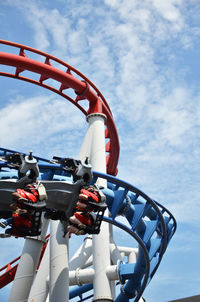 Low angle view of people enjoying rollercoaster against sky