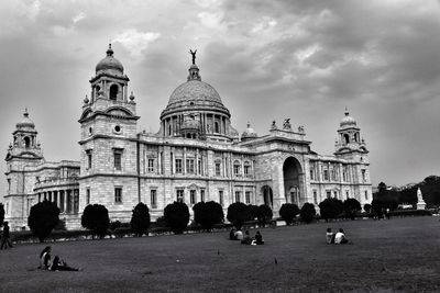 Tourists in front of church against cloudy sky