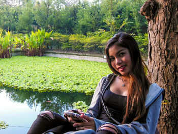 Beautiful young woman using mobile phone while sitting in park