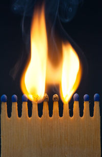 Close-up of burning matchsticks against black background