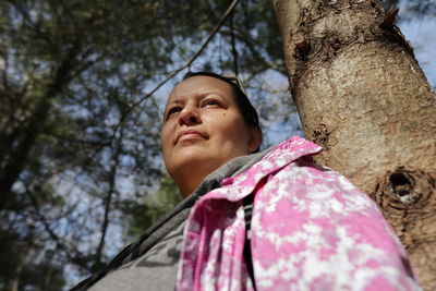 Portrait of young woman standing against tree