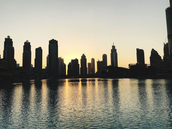 River by buildings against clear sky during sunset