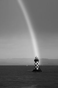 Lighthouse by sea against sky