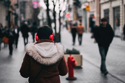 Rear view of woman walking on street during winter