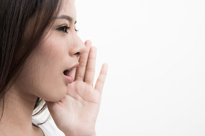 Side view of young woman whispering over white background